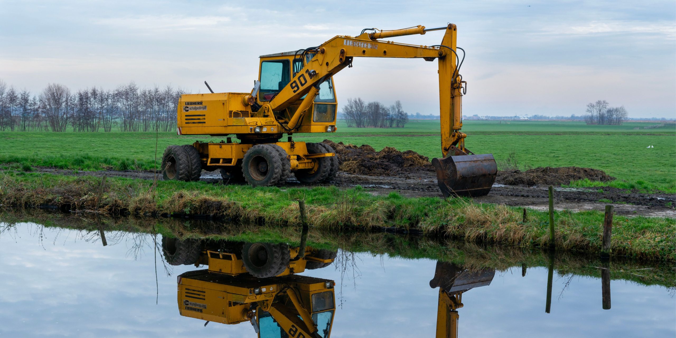 Graafmachine tijdens grondwerk langs een watergang