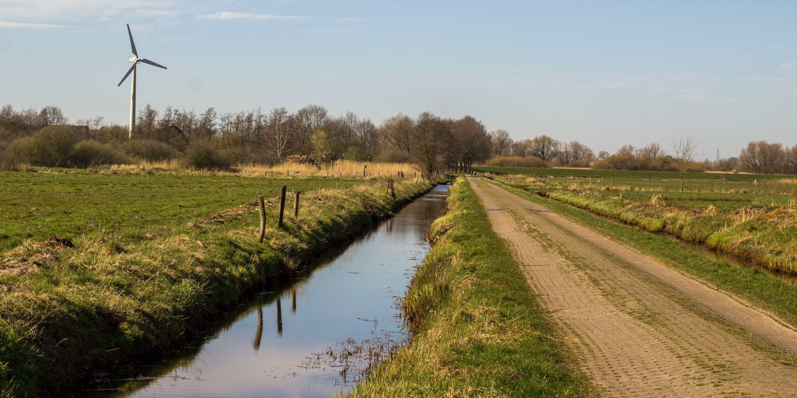 Nederlands landschap met water, weilanden en een windturbine
